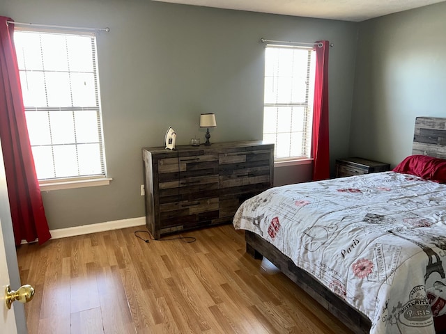 bedroom featuring light wood-style flooring, multiple windows, and baseboards