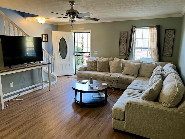 living area featuring ornamental molding, wood finished floors, a textured ceiling, and stairs