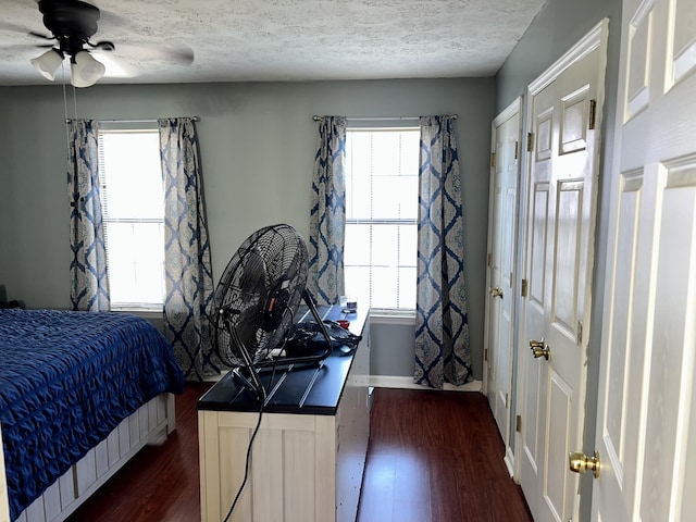 bedroom featuring dark wood-type flooring, a textured ceiling, baseboards, and a ceiling fan