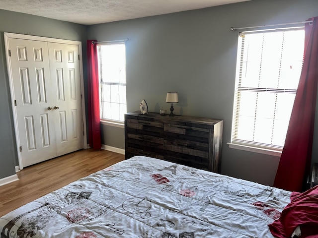 bedroom featuring a textured ceiling, wood finished floors, and baseboards