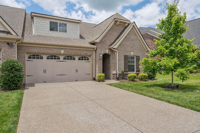 view of front of property with a garage, driveway, brick siding, and a front yard