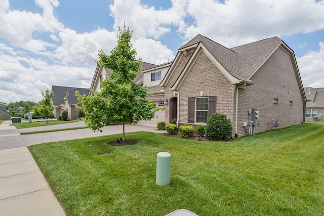 view of front of property with a garage, a shingled roof, concrete driveway, a front lawn, and brick siding