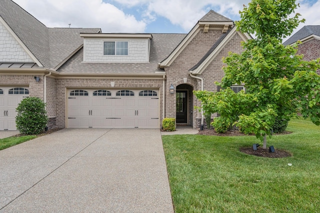 view of front of home featuring brick siding, roof with shingles, a garage, driveway, and a front lawn