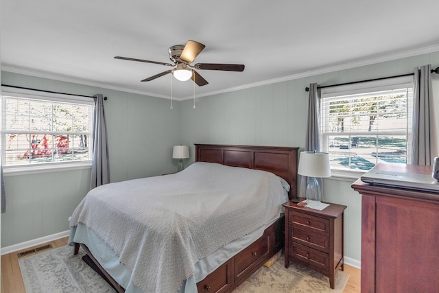 bedroom featuring ceiling fan, light wood-type flooring, visible vents, and crown molding