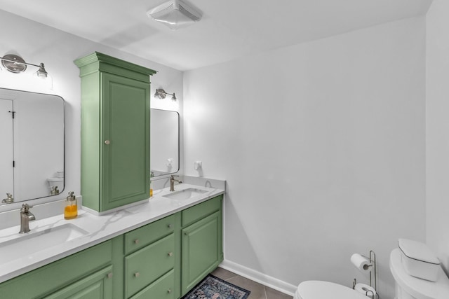 bathroom featuring toilet, double vanity, a sink, and tile patterned floors