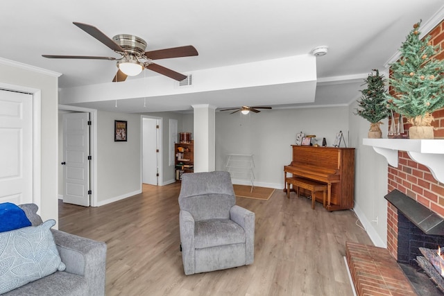 living room featuring baseboards, visible vents, light wood-style flooring, crown molding, and a fireplace