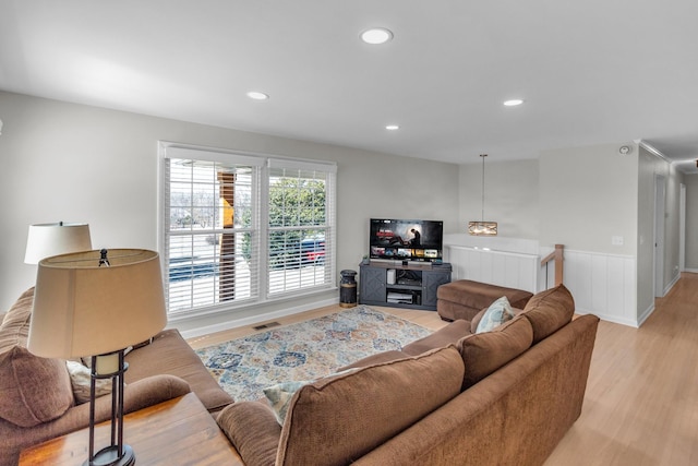 living area with light wood-type flooring, a wainscoted wall, visible vents, and recessed lighting