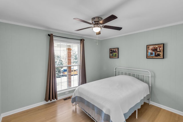 bedroom with crown molding, visible vents, light wood-style flooring, ceiling fan, and baseboards