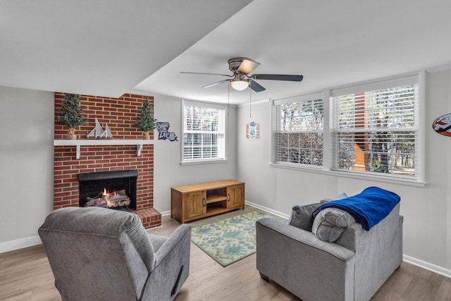 living room featuring a brick fireplace, baseboards, and wood finished floors