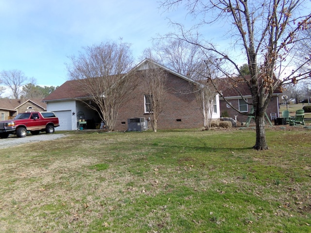 view of side of home with an attached garage, central air condition unit, brick siding, a yard, and crawl space