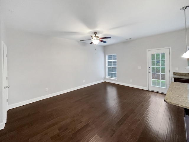 unfurnished living room featuring ceiling fan, dark wood finished floors, and baseboards