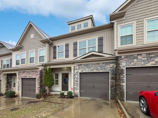 view of property with stone siding, board and batten siding, an attached garage, and driveway