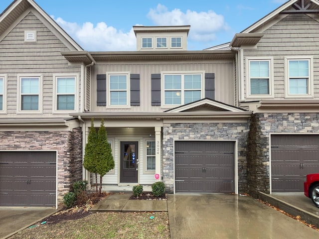 townhome / multi-family property with a garage, driveway, board and batten siding, and stone siding