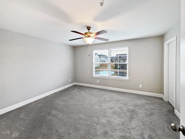 carpeted spare room featuring ceiling fan and baseboards