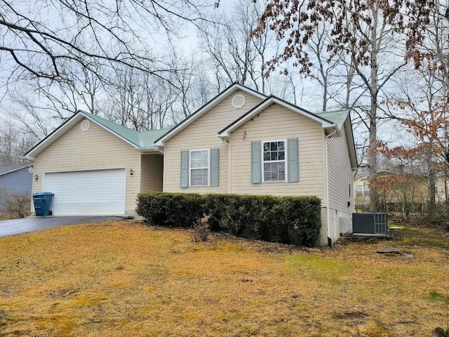 view of front of home with aphalt driveway, cooling unit, a front lawn, and an attached garage