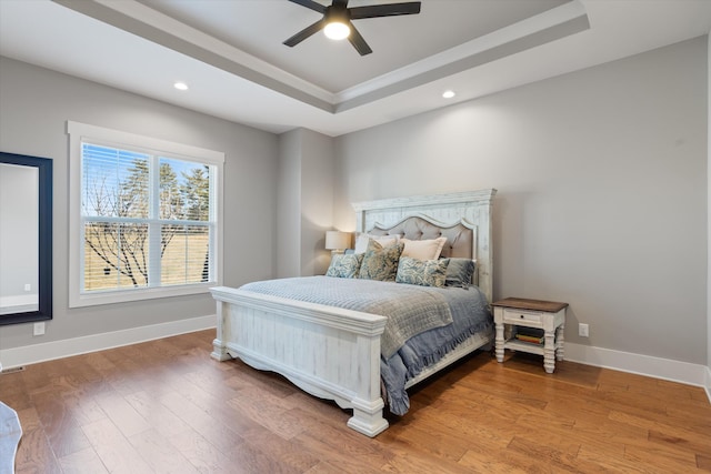 bedroom with recessed lighting, a raised ceiling, baseboards, and wood finished floors