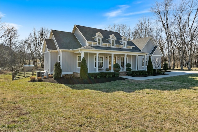 view of front of home with board and batten siding, a front yard, covered porch, and cooling unit