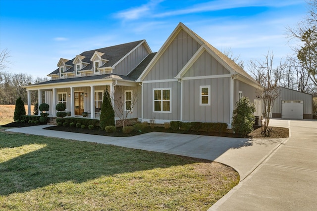 view of front of home with a detached garage, an outdoor structure, a porch, board and batten siding, and a front yard