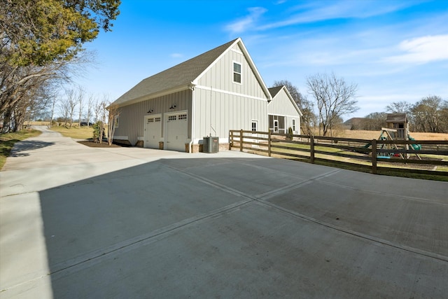 view of home's exterior with a garage, driveway, board and batten siding, and fence