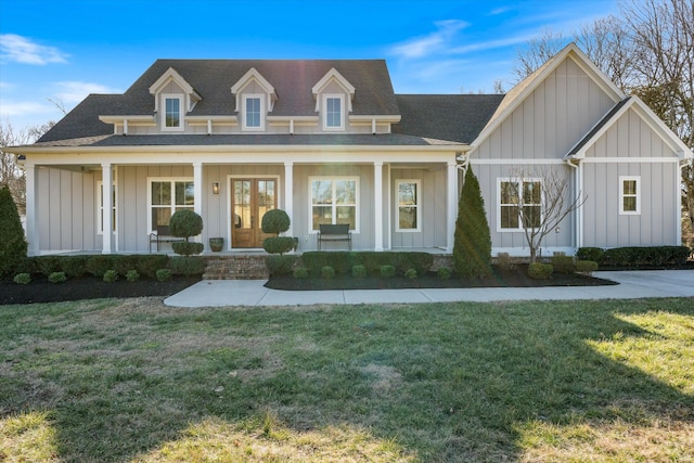 view of front facade with board and batten siding, a porch, a shingled roof, and a front lawn