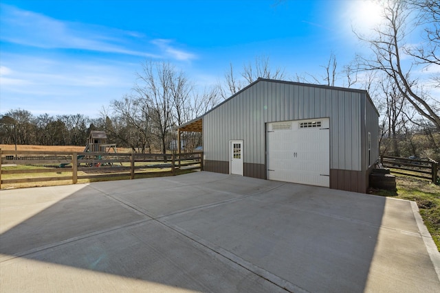 view of outdoor structure featuring an outbuilding, driveway, playground community, and fence