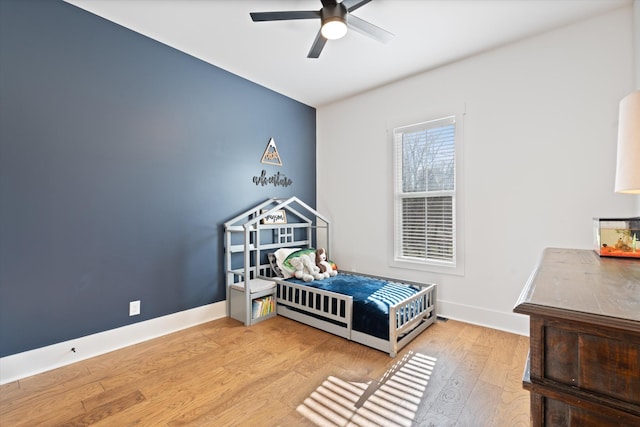 bedroom with a ceiling fan, baseboards, and wood finished floors