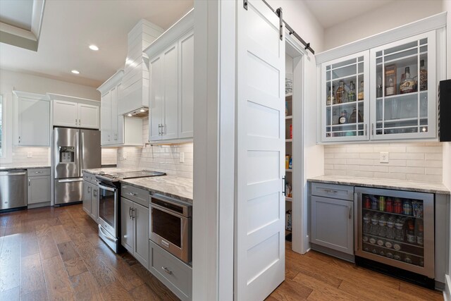 kitchen with wine cooler, a barn door, stainless steel appliances, dark wood-type flooring, and decorative backsplash