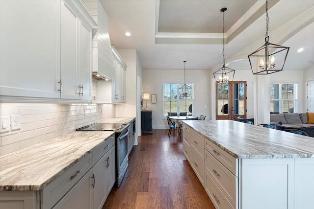 kitchen featuring tasteful backsplash, dark wood-style floors, a kitchen island, stainless steel electric range, and white cabinetry