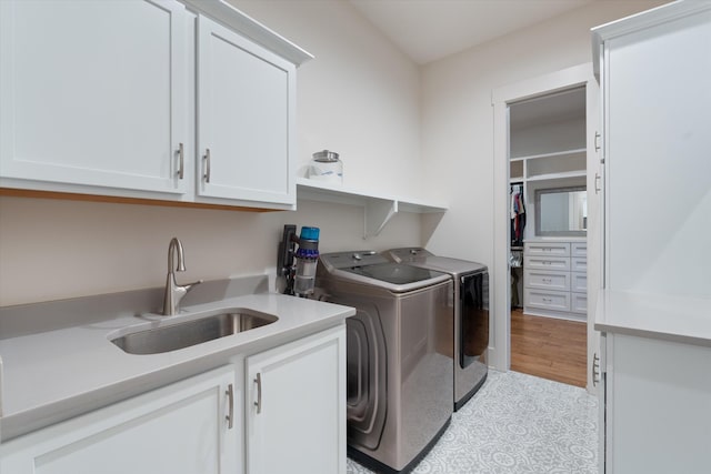 clothes washing area featuring cabinet space, a sink, and separate washer and dryer