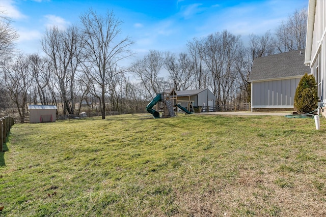 view of yard featuring an outbuilding, a shed, a playground, and fence