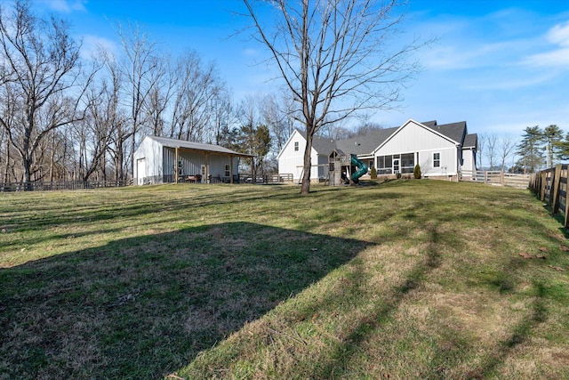 view of yard with fence, a playground, and an outbuilding