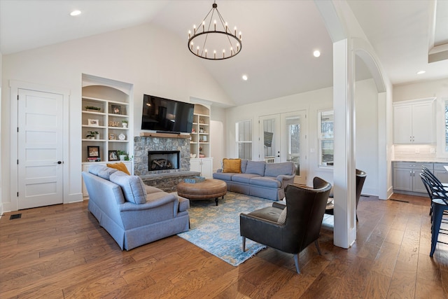 living area featuring high vaulted ceiling, recessed lighting, a fireplace, built in features, and wood-type flooring