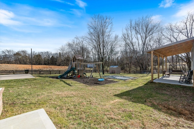 view of play area featuring a patio area, fence, a storage unit, and an outbuilding