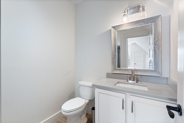 bathroom with baseboards, vanity, and toilet