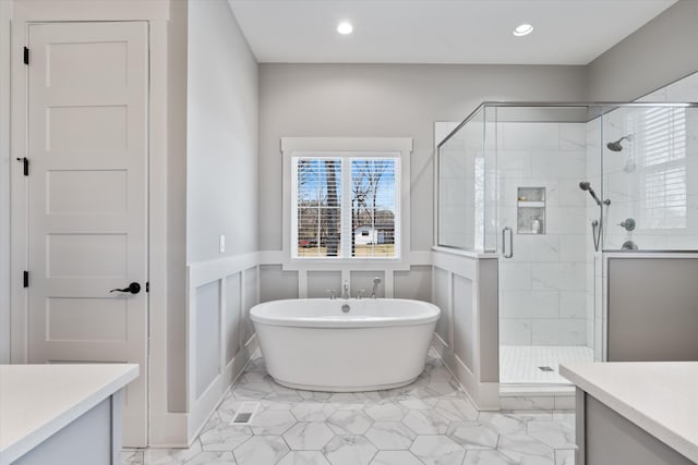 bathroom featuring a wainscoted wall, vanity, a freestanding bath, marble finish floor, and a shower stall