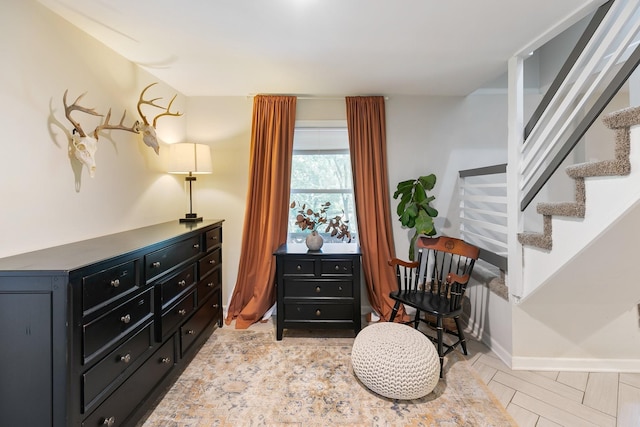 living area featuring stairs and baseboards