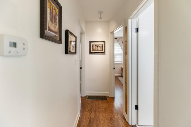 corridor with visible vents, baseboards, and wood finished floors