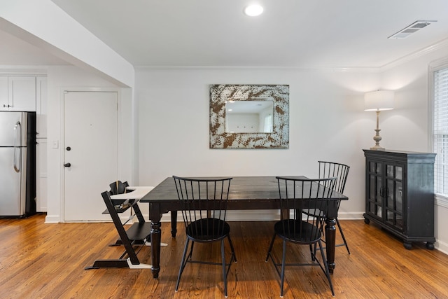 dining area with baseboards, visible vents, wood finished floors, and ornamental molding