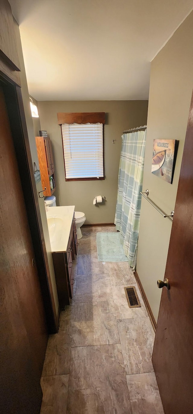 bathroom with baseboards, visible vents, a shower with shower curtain, toilet, and vanity