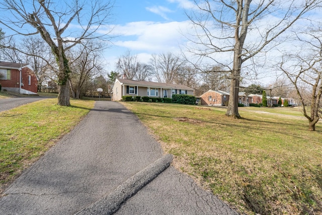 view of front of property featuring a chimney, a front lawn, and aphalt driveway