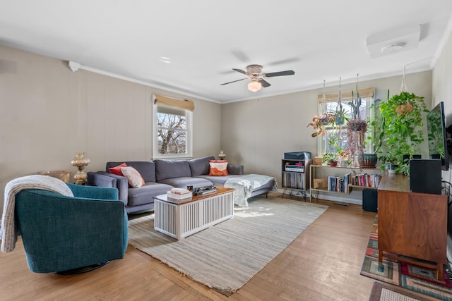 living room with plenty of natural light, crown molding, a ceiling fan, and wood finished floors