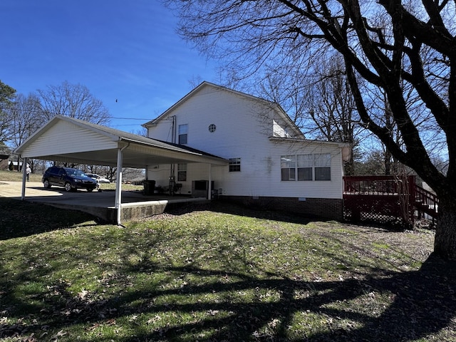 view of side of home with crawl space, a wooden deck, and a lawn