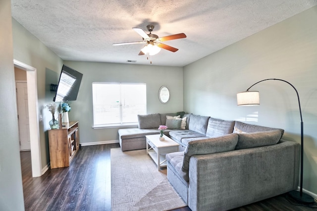 living room featuring ceiling fan, a textured ceiling, dark wood-type flooring, visible vents, and baseboards