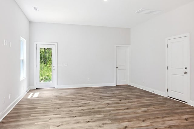 unfurnished room with baseboards, visible vents, and wood finished floors