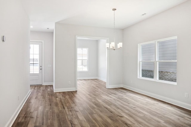 unfurnished dining area featuring a chandelier, wood finished floors, visible vents, and baseboards