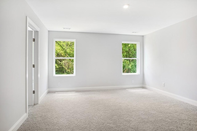 spare room featuring carpet flooring, visible vents, and baseboards