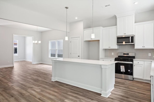 kitchen with wood finished floors, visible vents, appliances with stainless steel finishes, backsplash, and a center island