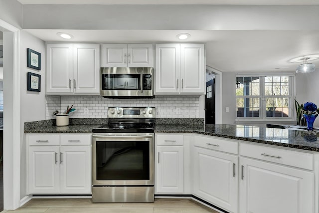 kitchen featuring appliances with stainless steel finishes, white cabinetry, backsplash, and dark stone countertops