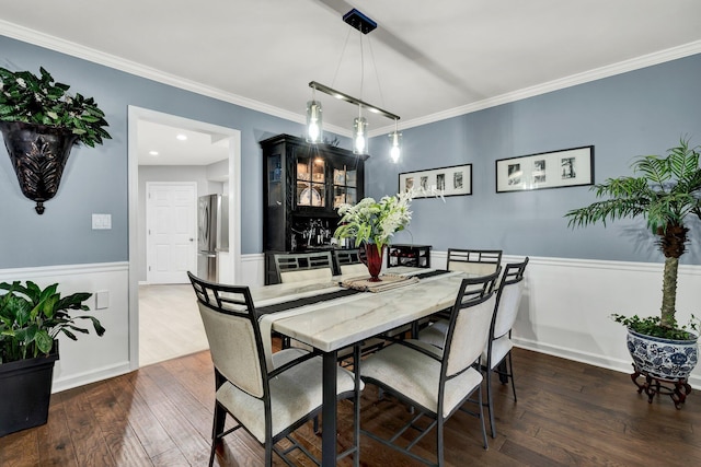 dining area featuring a wainscoted wall, dark wood-type flooring, and crown molding