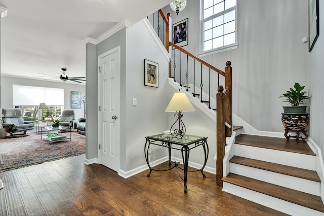 staircase with a healthy amount of sunlight, crown molding, baseboards, and wood finished floors